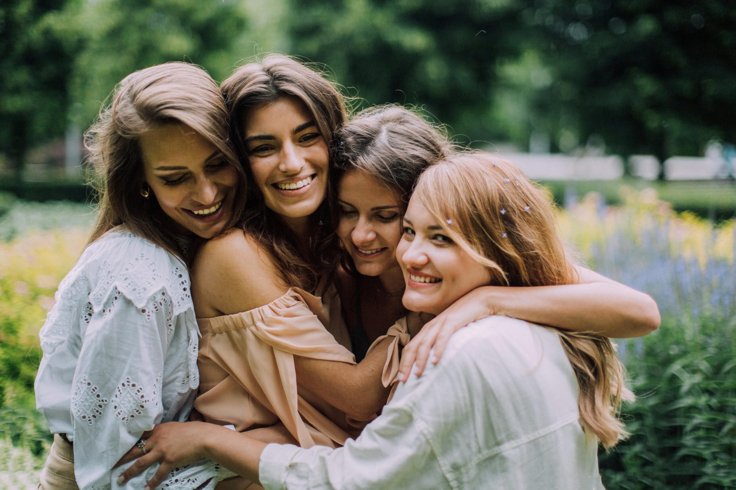 four women hugging in a field after visiting our cosmetic dentist North Brooklyn